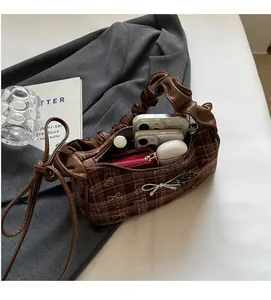 Spacious interior of brown checkered handbag showing storage for phone and cosmetics