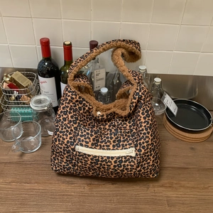 Detail of plush leopard print tote bag featuring a functional front zipper pocket