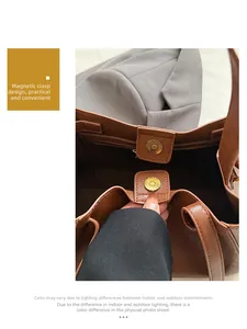 Detail of the golden magnetic buckle closure on a brown leather tote bag with inner pocket