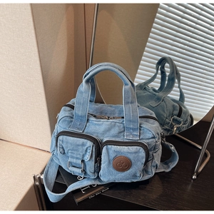 Detail view of denim crossbody bag showing multi-pocket texture and metal buckle accents