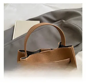 Detail of lychee pattern brown leather handbag featuring silver metal clasp and buckle