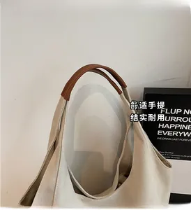 Close-up of beige canvas tote bag featuring premium brown leather reinforced handles