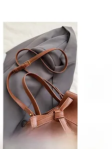 Detail of vintage brown leather tote bag with adjustable shoulder strap and bow ribbon