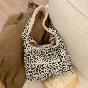 Detail of leopard print canvas tote bag with plush faux shearling trim and front zipper pocket