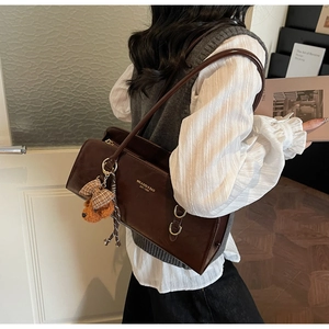Detalle de bolso bajo el brazo marrón vintage con osito de peluche y anilla en D dorada