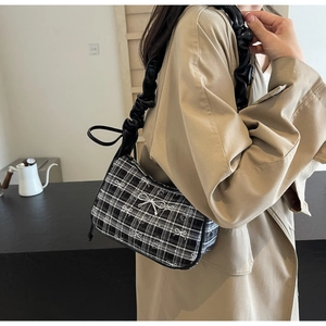 Detail of checkered shoulder bag featuring silver bow buckle and ruffled leather strap
