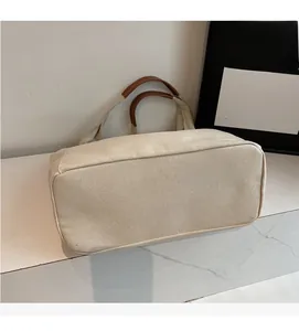 Macro detail of the cream canvas tote bag with reinforced brown leather handle stitching