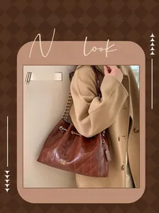 Detail einer braunen gesteppten Leder-Tote mit goldener PAN TOR Logo und Kettenriemen