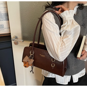 Detalle de bolso tote retro marrón oscuro con acabado encerado y colgante de osito