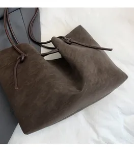 Detail of soft dark brown fabric tote with knot design and round rope handles