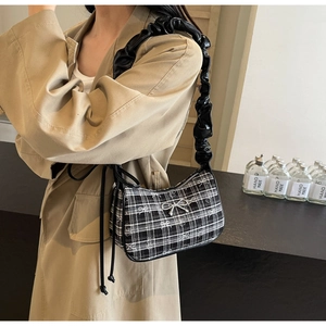 Close-up of checkered underarm bag with silver bow detail and pleated leather strap