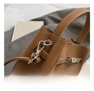 Close-up of silver metal hook and strap detail on brown lychee grain leather handbag