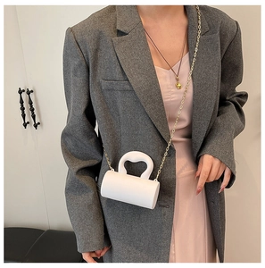 Gros plan d'un mini sac cylindrique blanc avec chaîne dorée et poignée stylée