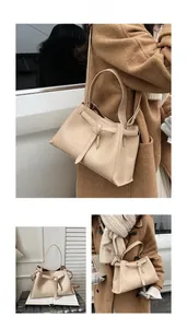 Detail showing the cream bucket bag's knotted decorative strap and smooth leather texture