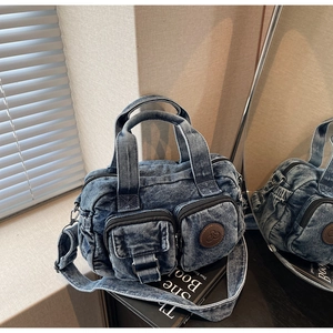 Detail of vintage blue denim bag with dual front pockets and leather logo accent