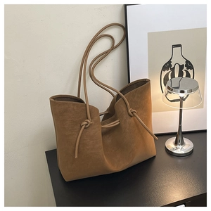 Close-up of brown suede tote bag featuring designer knotted shoulder strap details