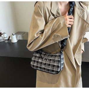 Detail of tartan underarm bag with white bow patterns and silver metallic bow buckle