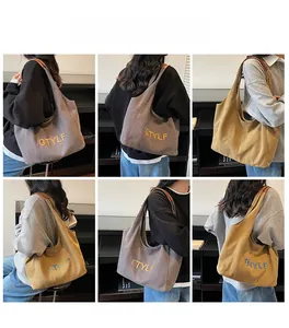 Detail view of large canvas tote bags in grey and yellow with embroidered GTYLF letters