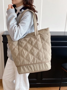 Quilted khaki tote bag with large diamond stitching worn by model for daily commute