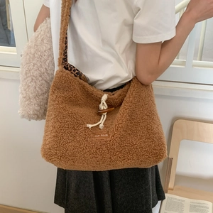Detail of plush crossbody bag featuring horn buckle closure and leopard print lining