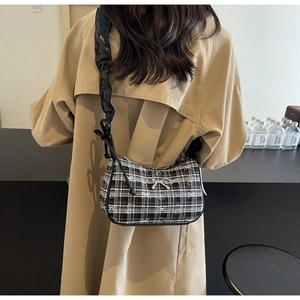 Detail of checkered shoulder bag with silver bow and pleated leather strap on model