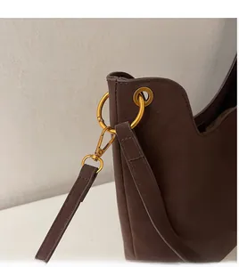 Detail of durable gold metal hook and buckle on brown matte leather shoulder bag