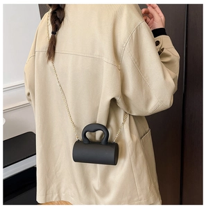Mini sac cylindrique noir minimaliste en acrylique avec chaîne dorée et poignée incurvée