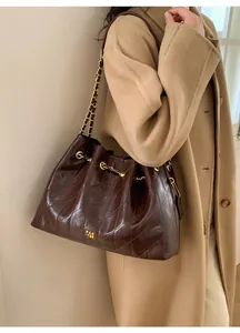Detailaufnahme der braun gesteppten Ledertasche mit goldener Kette und Logo-Akzent