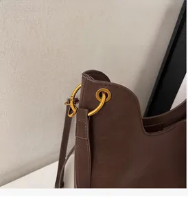 Detail of matte brown leather tote bag with vintage round gold hardware and thin strap