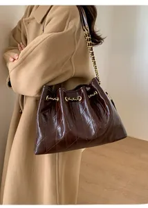 Detailansicht der dunkelbraunen Stepptasche mit Goldkette und Metall-Logo-Emblem