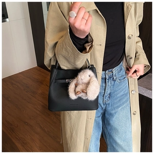 Detail of black faux leather bucket bag with pink bunny charm and adjustable strap