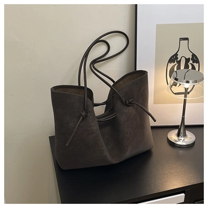 Detailed view of dark brown matte leather tote bag with unique knot accents and long handles