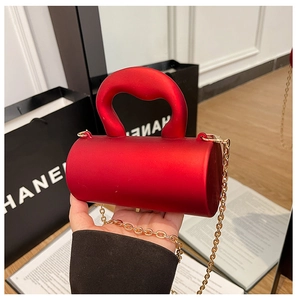 Gros plan détaillé d'un mini sac cylindrique rouge avec bandoulière en chaîne dorée