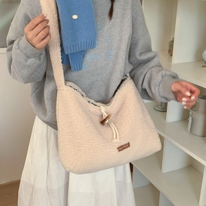 Detail of cream fleece crossbody bag featuring a classic toggle closure and leather tag