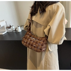 Close-up of brown plaid shoulder bag with silver bow detail and bear pattern