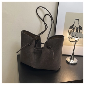 Detail of the soft dark brown tote bag showing the knotted strap and matte leather texture