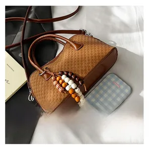 Detailed view of brown woven baguette bag with wooden beads and adjustable shoulder strap