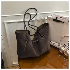 Detail of dark brown suede tote bag featuring refined knot detail and soft leather texture