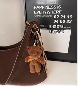Detail of dark brown faux leather tote with plush bear charm and woven rope accent
