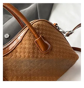 Détails d'un sac tressé marron montrant les crochets en métal et la fermeture éclair