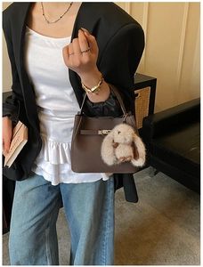 Detail of vintage brown leather bucket bag with metal lock and plush rabbit charm