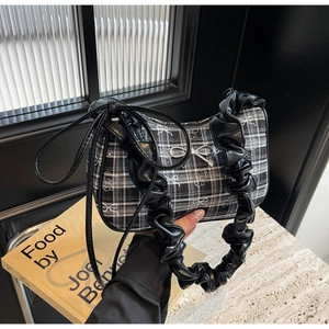 Detail of checkered shoulder bag featuring silver bow and black ruffle leather straps