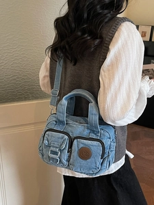 Stylish blue denim crossbody bag with dual pockets and adjustable strap on a female model