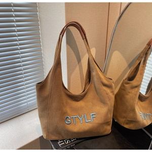 Close-up of brown canvas tote bag with blue GTYLF embroidery and leather handle grip