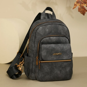 Detail of dark grey backpack with gold hardware and Jingpin logo in warm autumn setting