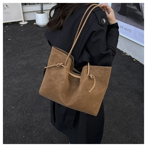 Detail of retro brown tote bag with knotted shoulder strap texture and matte finish