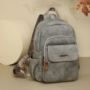Macro detail of grey leather backpack texture and bronze metal logo with zip pockets