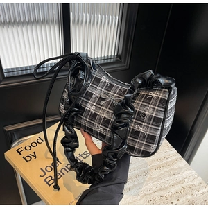 Close-up of black and white plaid handbag with ruffle handles and bow detailing