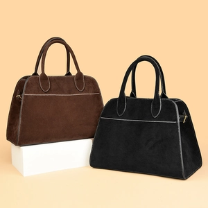 Detail view of large tote bags in brown and black suede with contrast white stitching