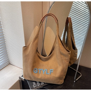 Detail of tan canvas tote bag with blue GTYLF embroidery and faux leather handles